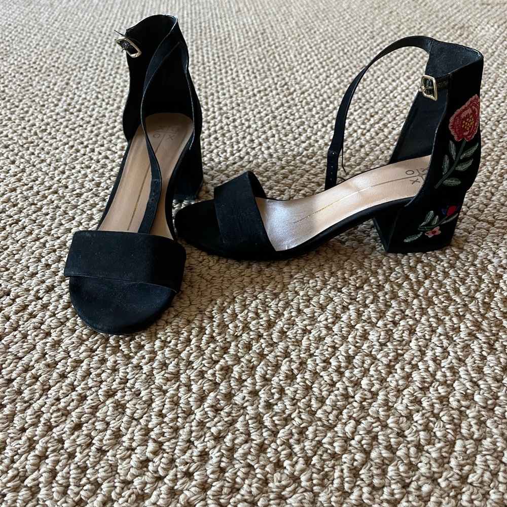 Black heeled sandals with floral detailing in the back.